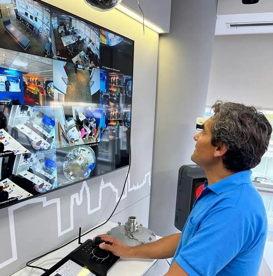 Sebastián maneja una cámara PTZ con un joystick, frente a un videowall que muestra dieciséis cámaras a la vez.